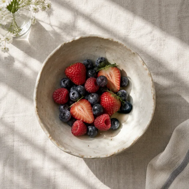 Ceramic bowl with berries on linen in morning light